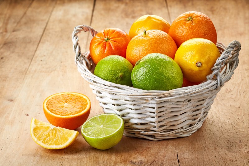 Basket of citrus fruits on wooden background