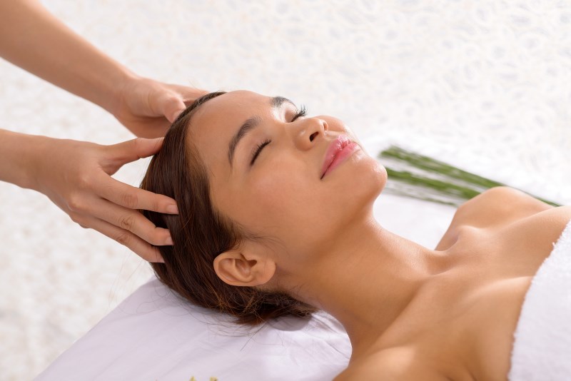 Asian young woman enjoying scalp massage in spa salon