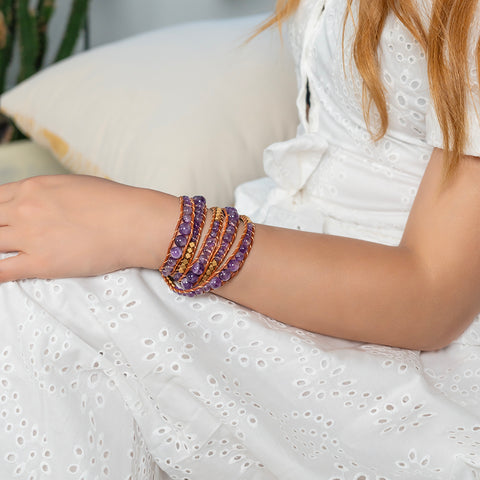 A woman wearing a five-layer purple Amethyst wrap bracelet with gold accent beads and tan leather cord.