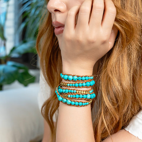 A woman wearing a multi-layer Turquoise and gold bead wrap bracelet on her wrist.