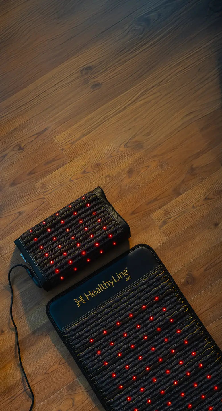 HealthyLine Jet Mat 7224 and Jet Pillow with active red infrared LEDs placed side by side on a hardwood floor