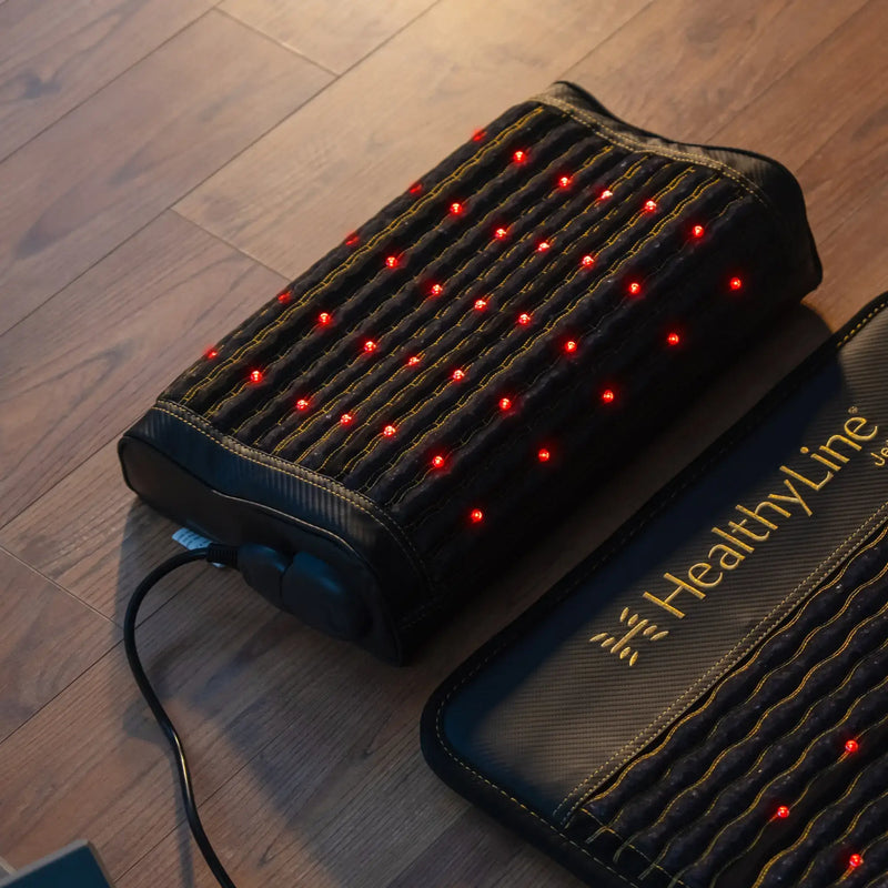 HealthyLine Jet infrared pillow with glowing red LEDs resting on a Jet mat, both on hardwood floor