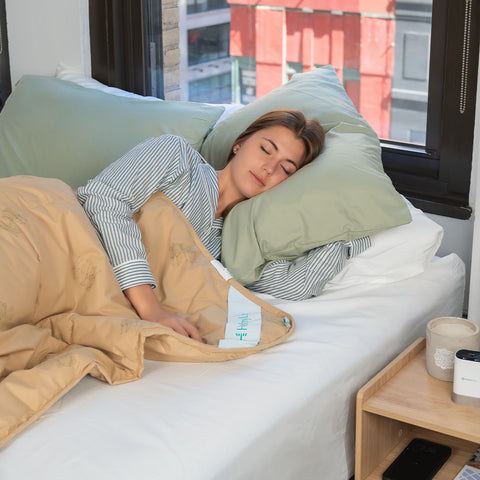 A woman sleeps comfortably in a bright bedroom under a tan HealthyLine 300 GSM natural camel hair winter comforter.