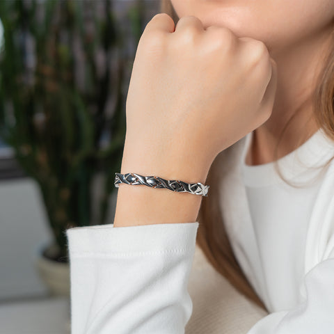 A woman wearing a stainless Steel Energy Bracelet 4-in-1 Silver color Models B032 featuring magnets and negative ions for energy and wellness
