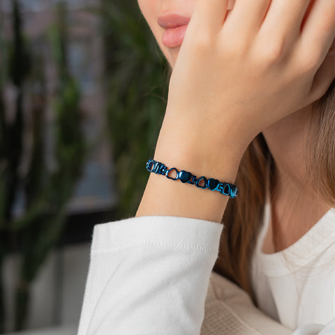 A woman wearing a blue heart-shaped stainless steel energy bracelet on her wrist.