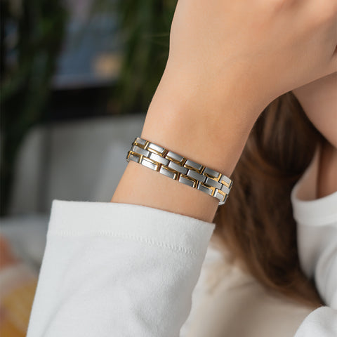 A woman wearing a silver stainless steel energy bracelet with figure-eight links on her wrist.