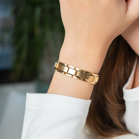 A woman wearing a gold-plated stainless steel energy bracelet with classic three-row links.
