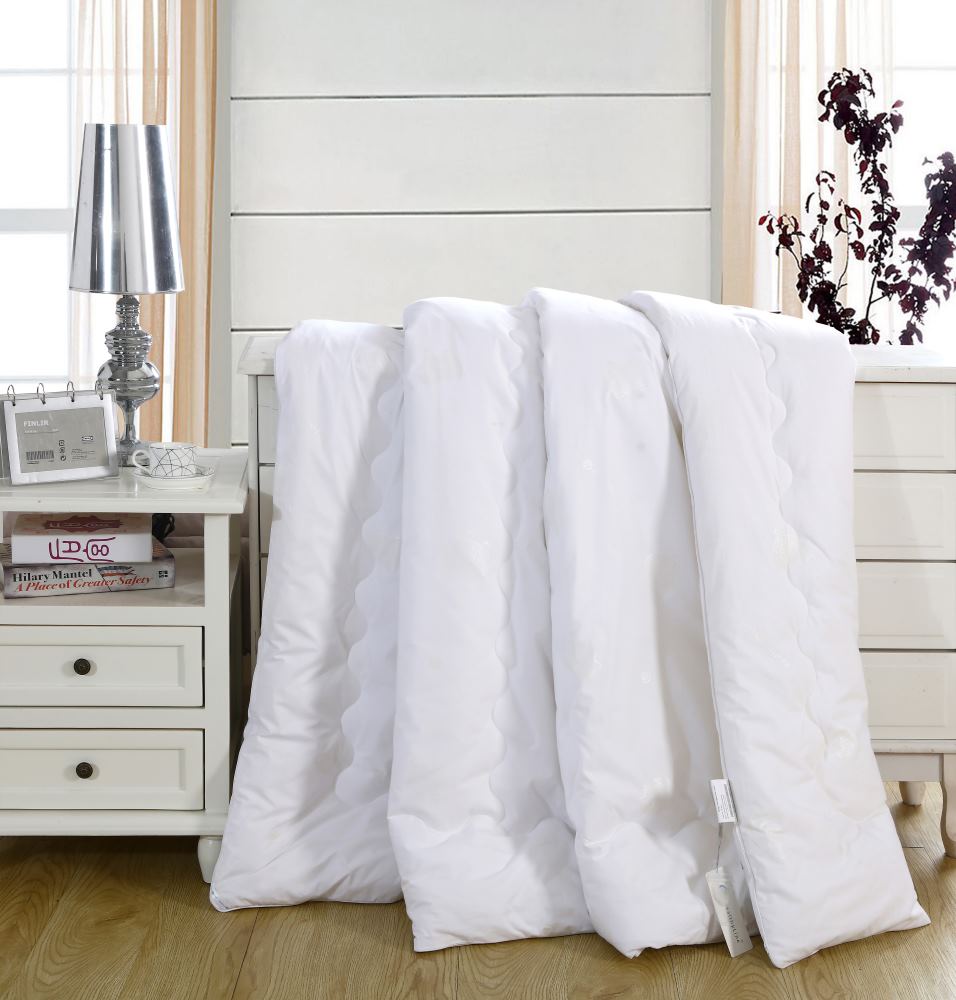 A white HealthyLine Magnetic Energy Comforter draped over a white dresser, showing its thick, quilted design.
