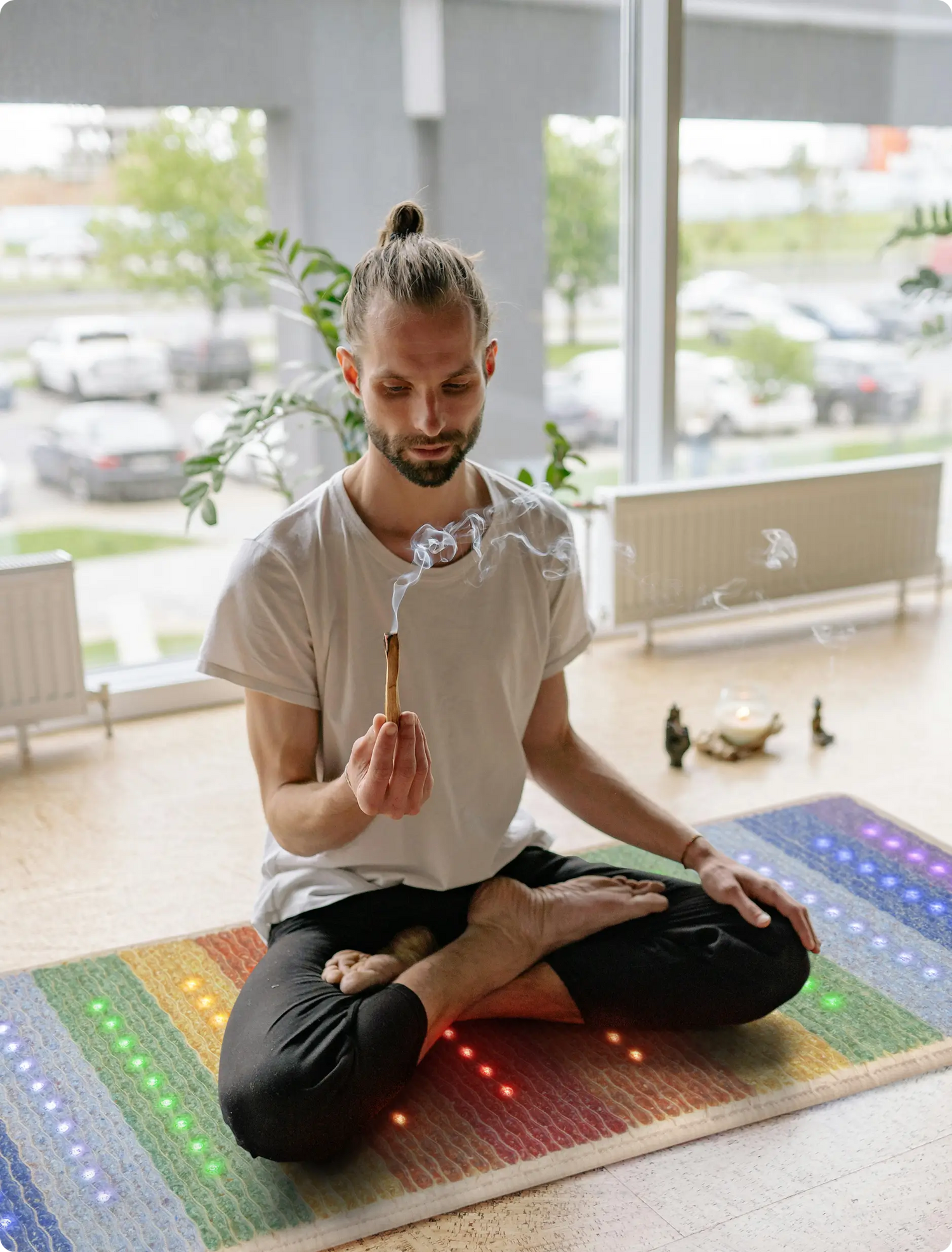 Man meditating cross-legged with incense on a HealthyLine Rainbow 74x28 mat with multicolor light nodes