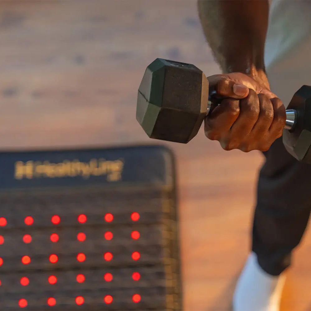 Person holding a dumbbell over a HealthyLine Jet Mat 4024 with glowing red light LEDs on a gym floor