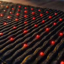 Close-up of the Jet mat surface showing the dark fabric with wave-pattern gemstone channels and evenly spaced red photon lights across the full mat