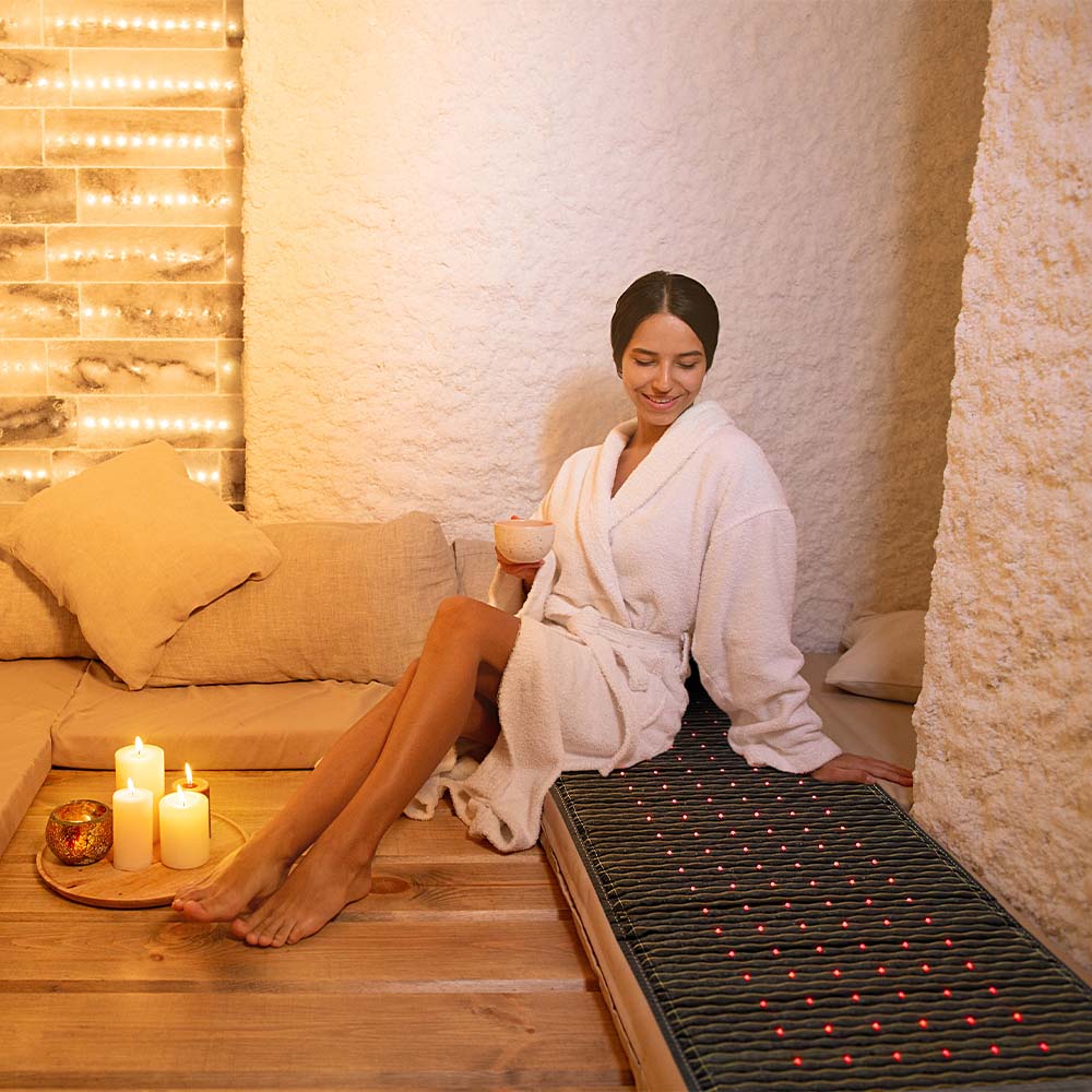 A person is sitting on a Jet 72x24 mat placed on the floor inside a salt room environment
