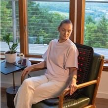 Person relaxing on a sofa with the Jet 40x18 mat across their back, red photon lights glowing