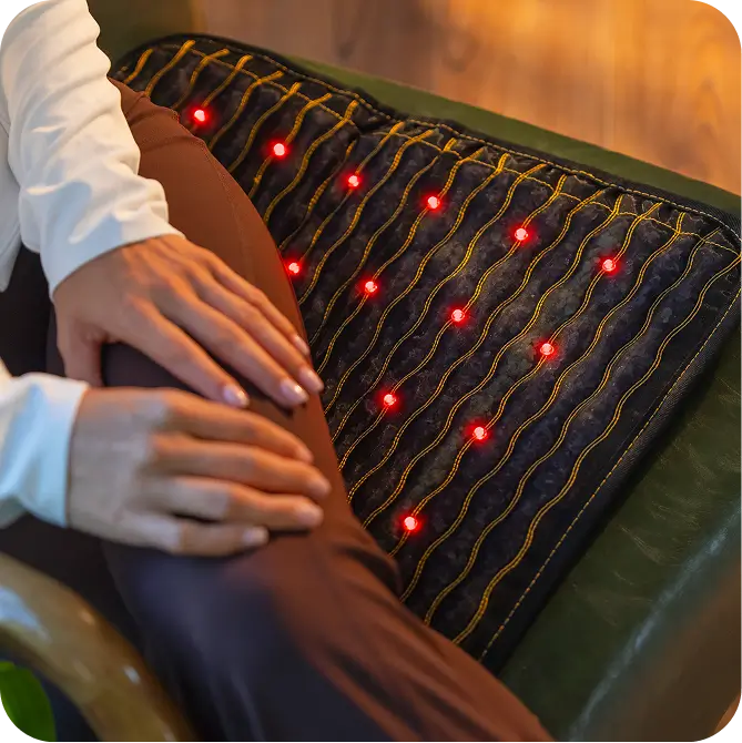 Person seated using the Jet mat 20x20 on a chair with red light therapy LEDs illuminated
