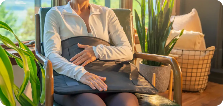 Person seated in an armchair with the Jet mat 20x20 placed on their lap and abdomen