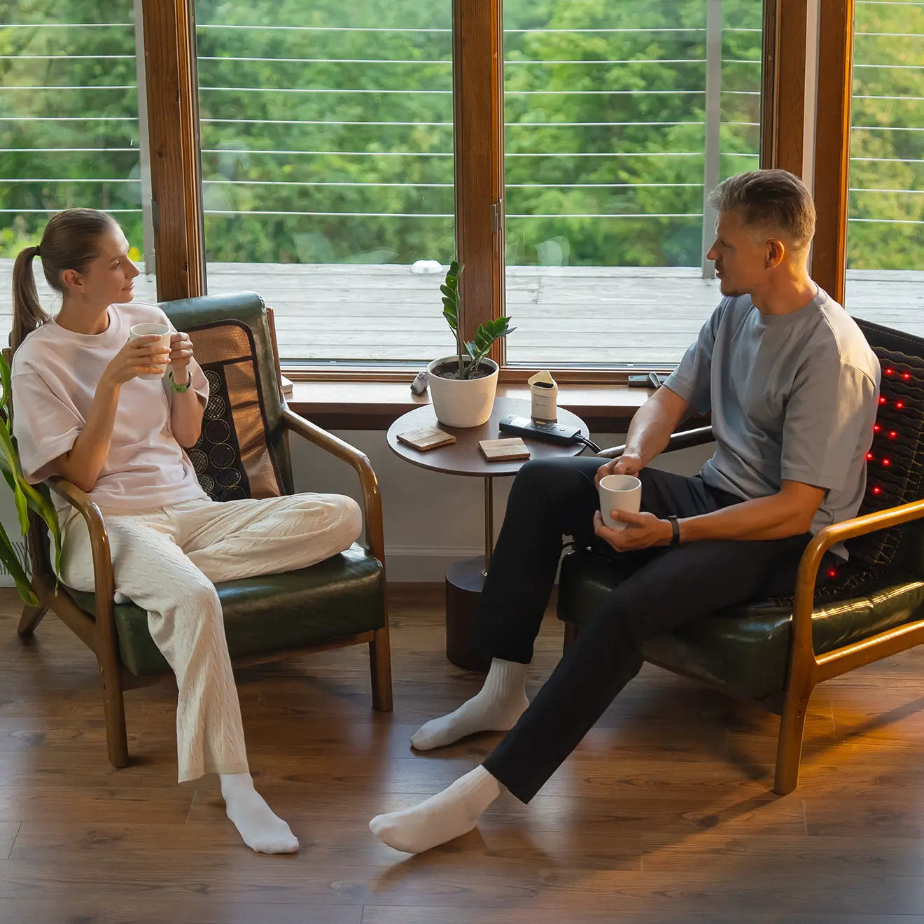 Woman on a chair with a HealthyLine MESH 3220 mat and man with a JET 40x18 chair mat with active red LEDs, chatting over coffee