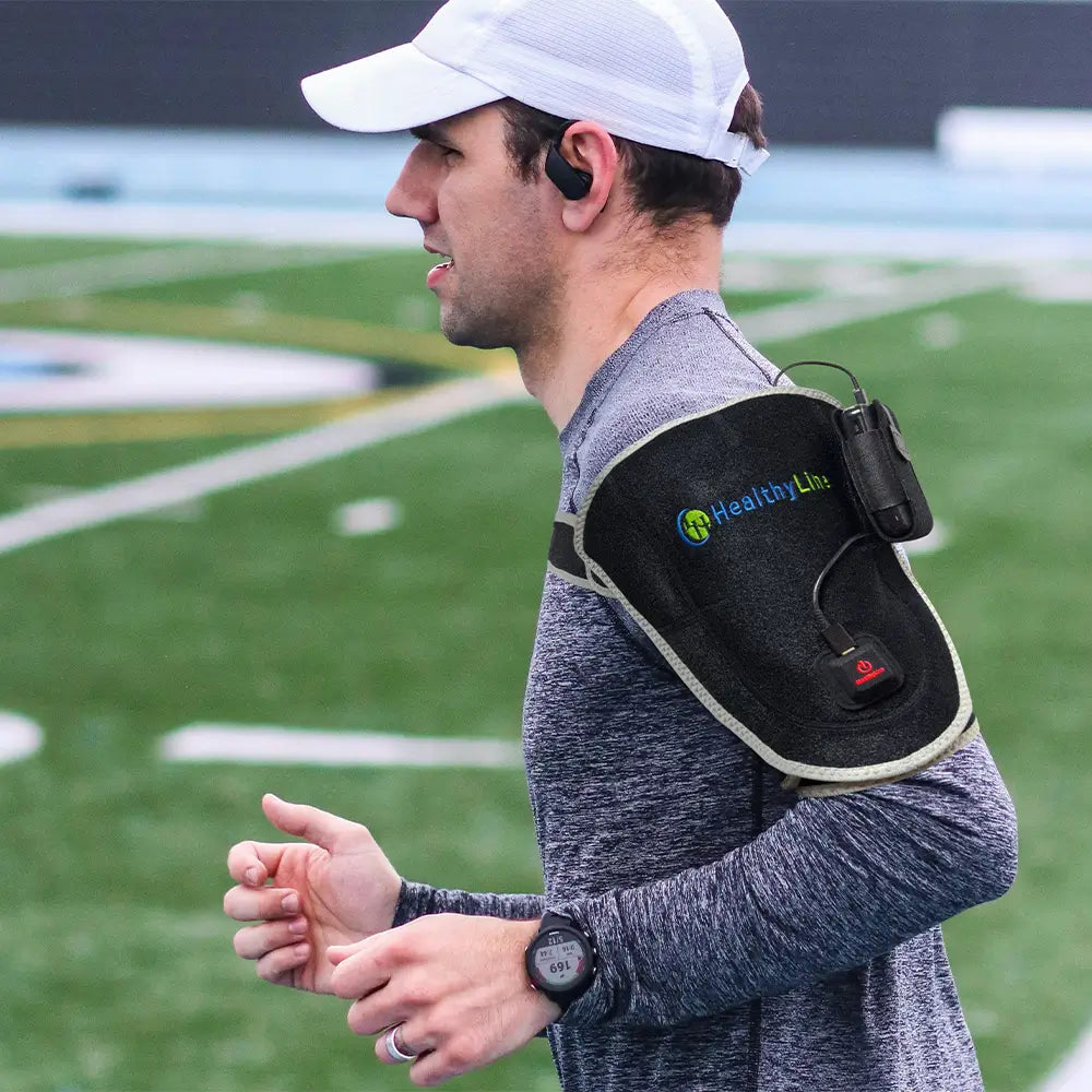 Man wearing a HealthyLine portable heat therapy shoulder wrap while holding a water bottle
