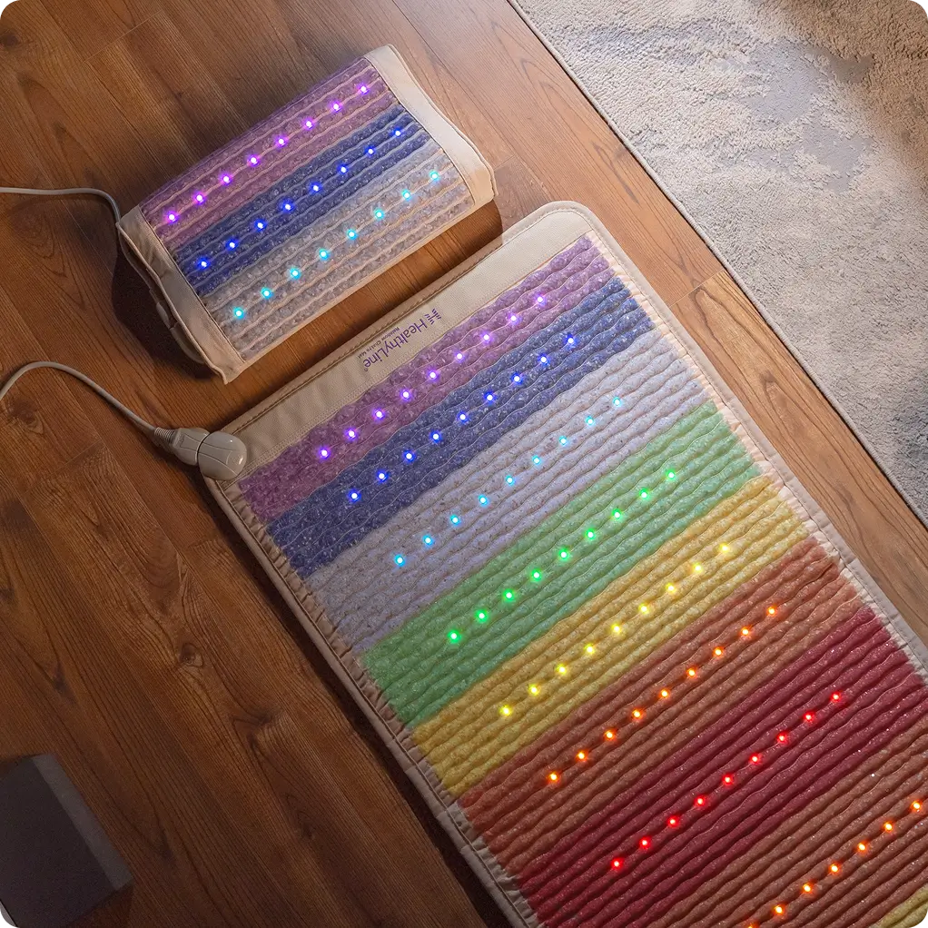 HealthyLine Rainbow Chakra Mat 7428 and matching pillow on hardwood floor, both displaying full-spectrum chakra-colored LEDs