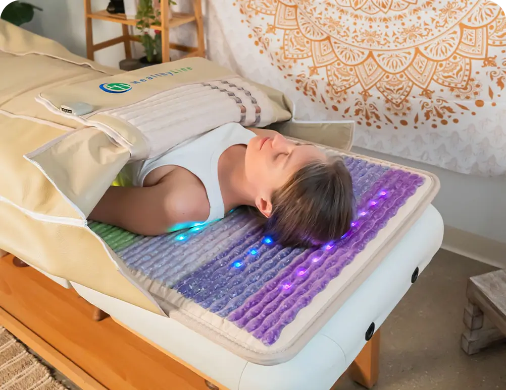 Woman resting on the HealthyLine Rainbow Chakra Mat 7428 with blue and violet LEDs glowing beneath her head at a spa