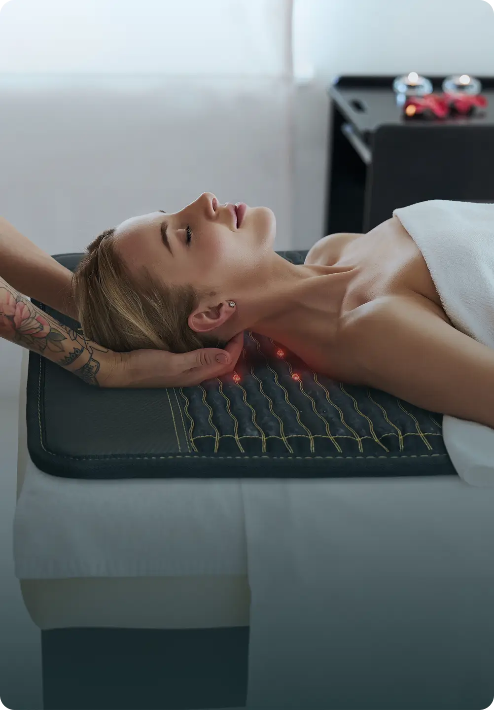 Woman lying on the HealthyLine Jet Mat 7428 receiving a neck massage in a spa, with red infrared LEDs visible