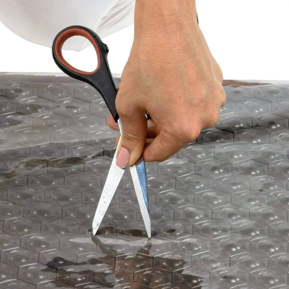 Close-up of the Tourmaline Pet Mat Large 5024's water-beaded, scratch-resistant surface with scissors
