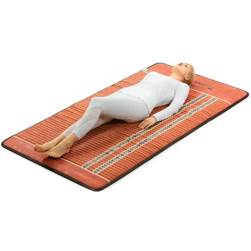 Person lying on the TAO 8040 Extra Large mat in red fabric with gemstone rows visible
