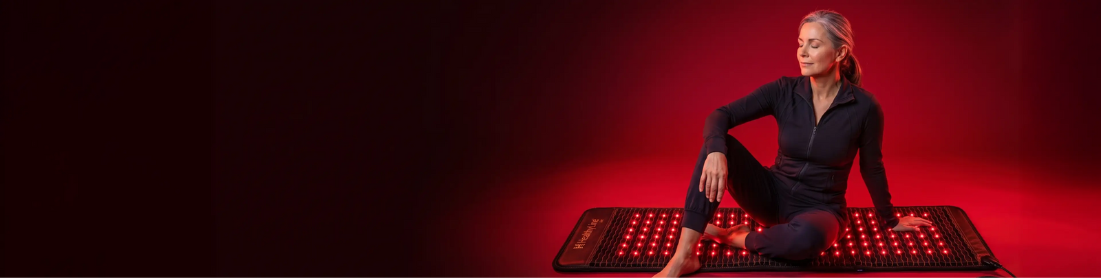 Woman sitting cross-legged on Jet 6024 red light therapy mat, eyes closed