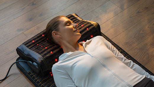 Woman relaxing on Jet 7224 red light therapy mat with matching heated pillow