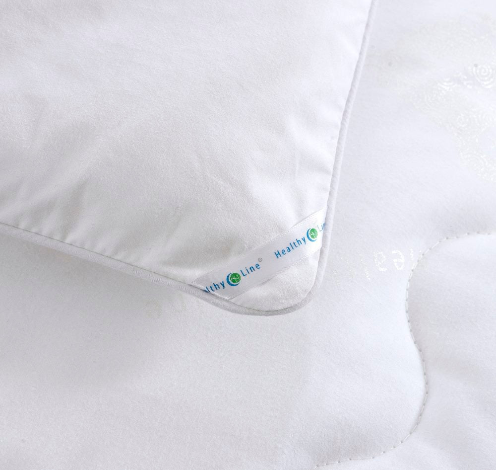 Close-up of a HealthyLine quilt's edge, featuring a satin brand ribbon and a detailed view of the piped perimeter
