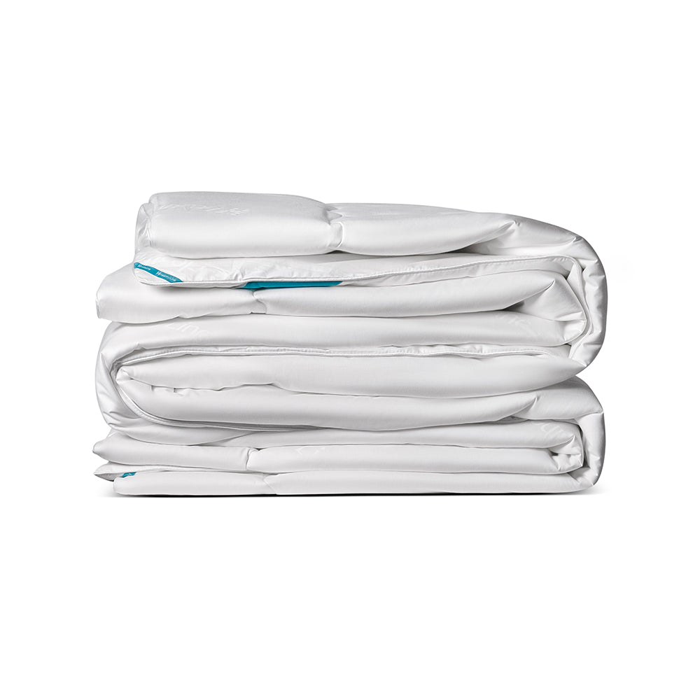 A white, quilted Magnetic Energy Comforter folded on a white background 
