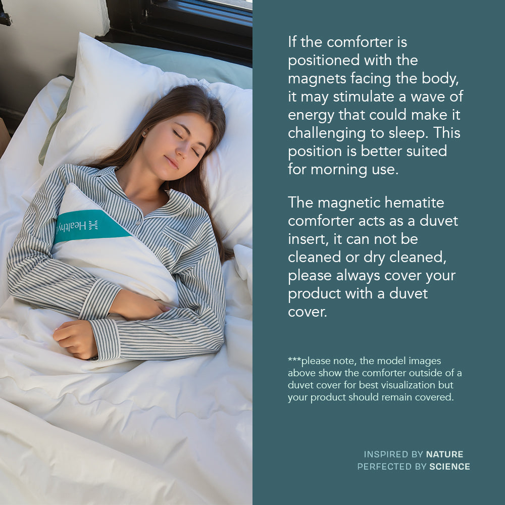 A woman sleeps under a HealthyLine silk hematite comforter next to text explaining magnetic orientation and care.
