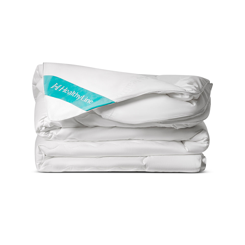 A white, quilted Magnetic Energy Comforter folded on a white background 
