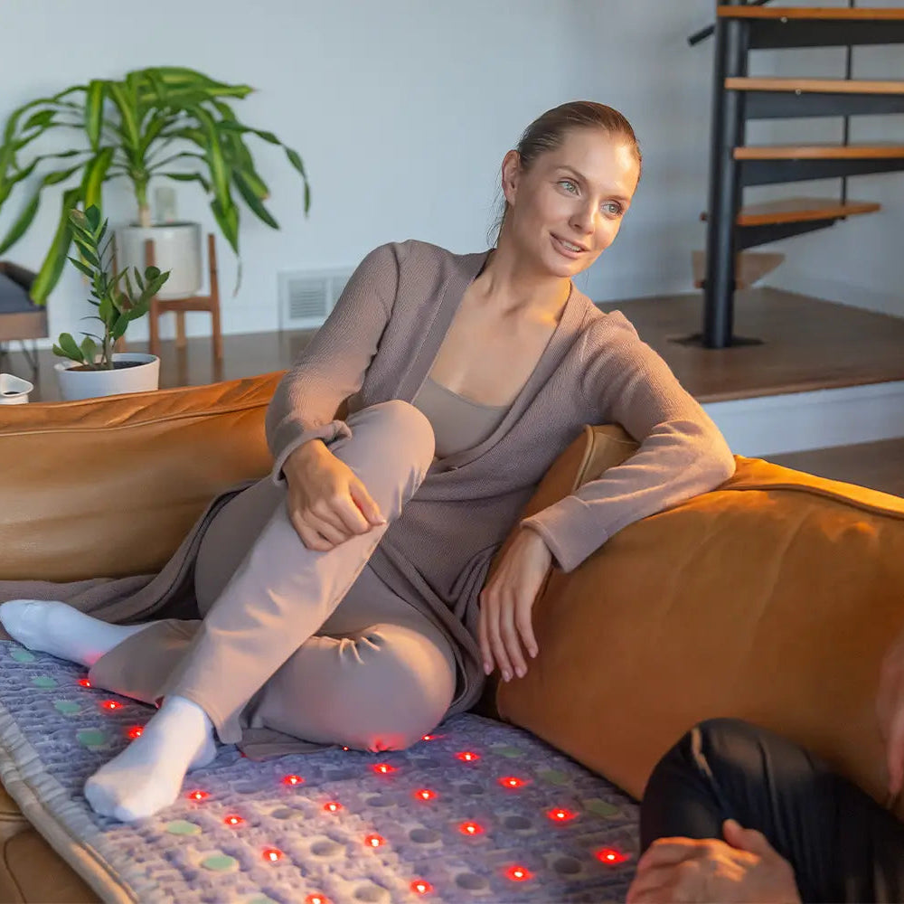 Person is sitting on TAJ 7224 HealthyLine mat placed on a brown sofa in the living room environment 