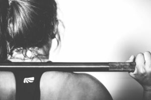 Woman working out with a barbell: How to Stick to a Workout Routine